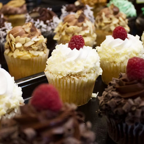 rows of cupcakes with raspberries on top